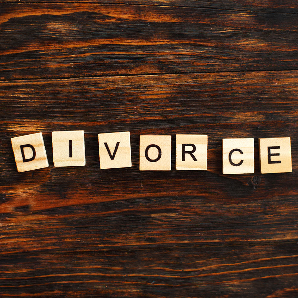 Scrabble tiles spelling out "Divorce" on a wood surface