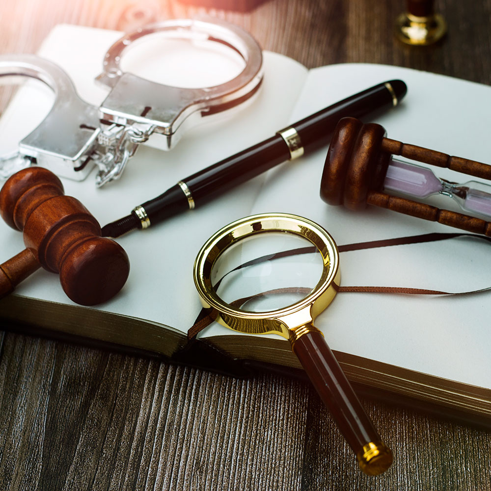 Magnifying glass, hourglass, gavel, pen, and handcuffs on an open book